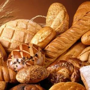 Primo piano di forme di pane con sulla sinistra un mazzo di spighe