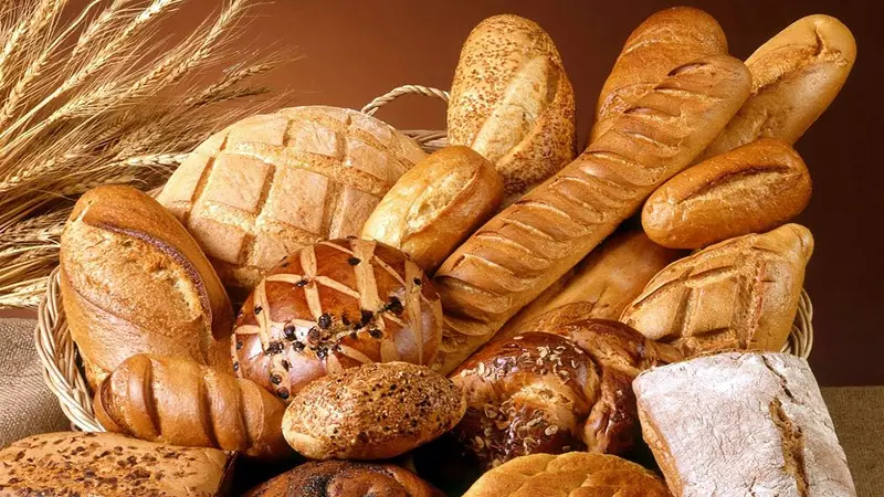 Primo piano di forme di pane con sulla sinistra un mazzo di spighe